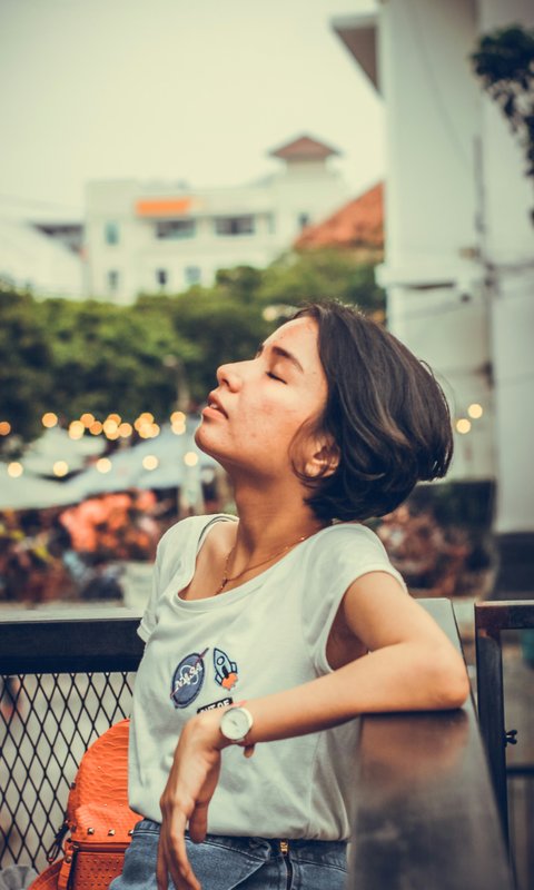 A young woman with her eyes closed, head tilted toward sunlight — her time, returned